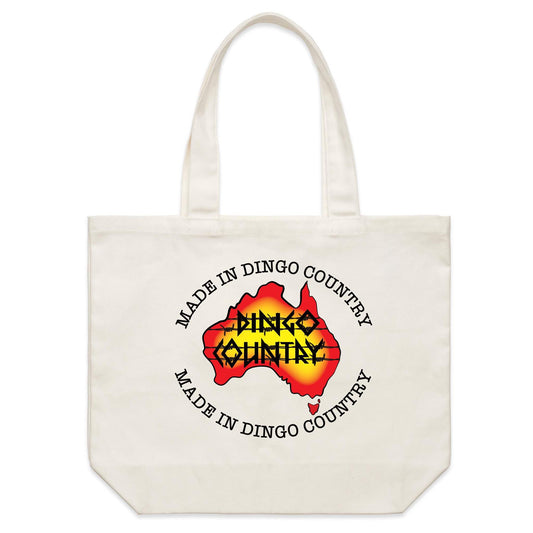 Canvas tote bag with 'Made in Dingo Country' text and a stylized map of Australia in red with yellow-orange flames in the center, symbolizing the Dingo Country. The design is centered on the bag's side, offering a striking contrast against the tote's natural color. Available for purchase at dingocountry.com.